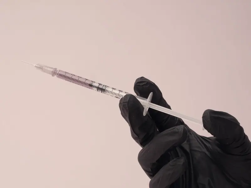A gloved hand holding a prepared syringe